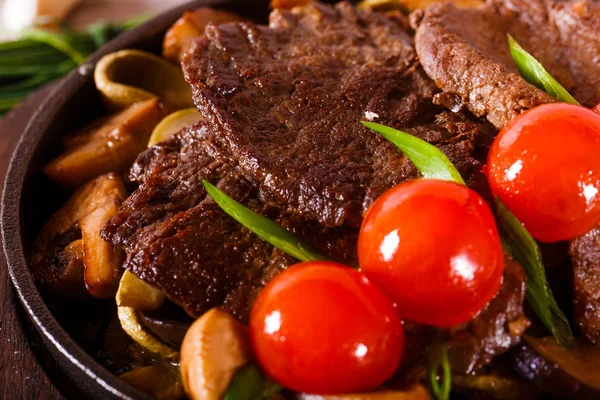 Carne frita em uma panela com tomates cereja — Fotografia de Stock