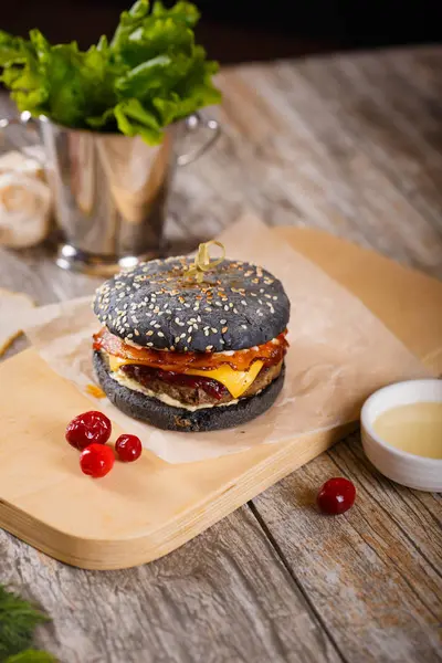 Pastırma ve sosu bir ahşap stand ile siyah hamburger Telifsiz Stok Imajlar