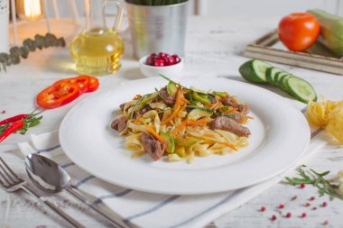Makarna beyaz tabakta zeytin et yeşillikleri ile