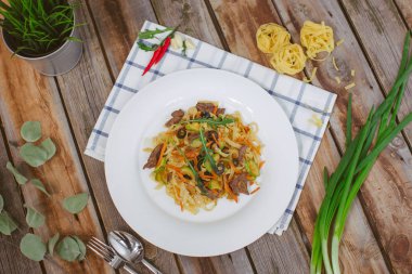 Makarna beyaz tabakta zeytin et yeşillikleri ile