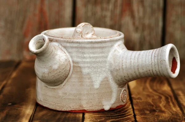 木製の背景に白い陶器の手作りティーポット — ストック写真