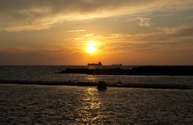 Deniz ve iki gemi siluetleri gün batımında