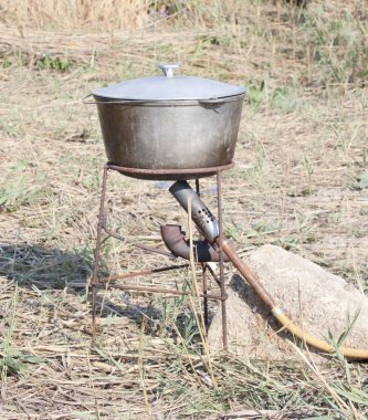 Banka nehrinde bir tripod üzerinde isli kazan