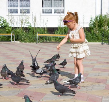 Mutlu Kızıl saçlı çocuk güvercin tahıl Meydanı'nda besleme.