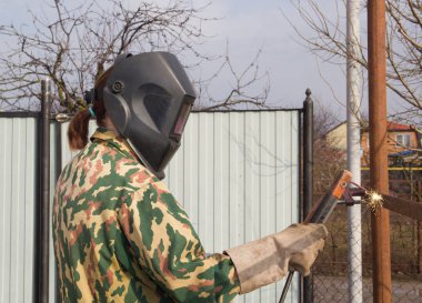 Kadın Kaynakçı metalden yapılmış bir çit bağlar