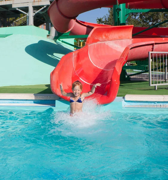 Hermoso niño pelirrojo en un tobogán en el parque acuático . — Foto de Stock