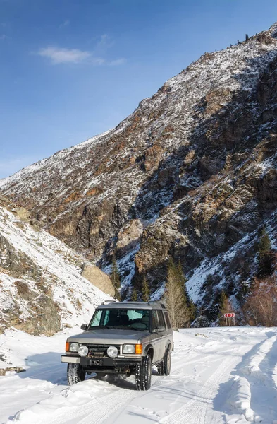 SUV em uma estrada de montanha nevada — Fotografia de Stock