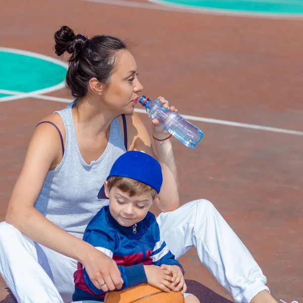 Mamá y su hijo descansando en la cancha de baloncesto —  Fotos de Stock