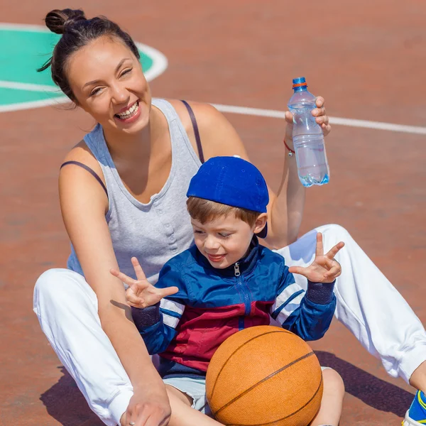Mama i syn, siedząc na boisko do koszykówki — Zdjęcie stockowe