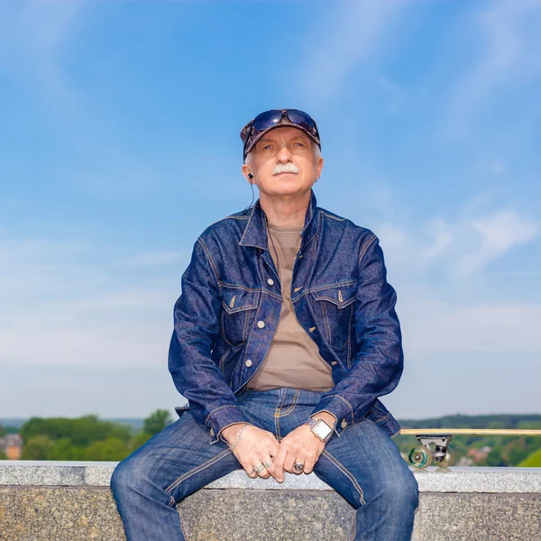 Senior man sitting with skateboard — Stock Photo, Image