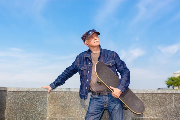 Homem sênior de pé com skate — Fotografia de Stock