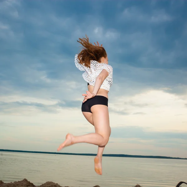 Dívka, která skočila na pláži při západu slunce — Stock fotografie