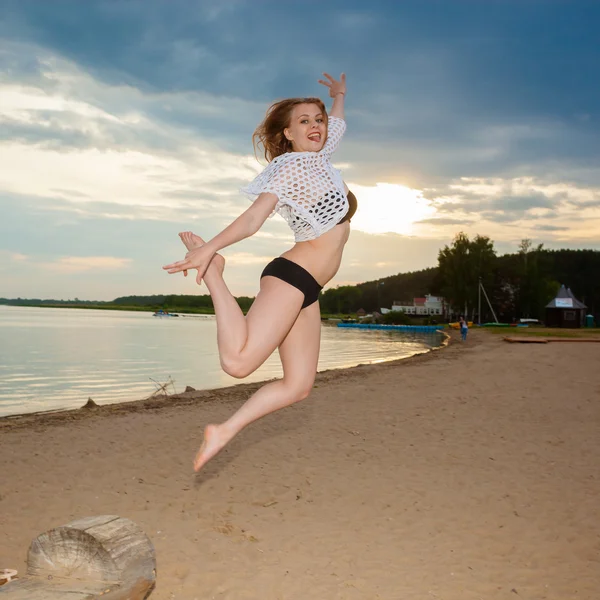 Дівчина стрибає на пляжі на заході сонця — стокове фото