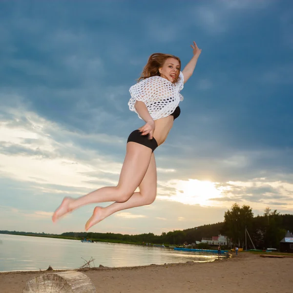 Chica saltando en la playa al atardecer — Foto de Stock