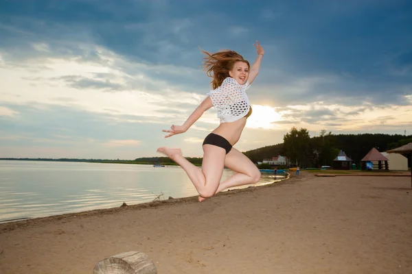 Дівчина стрибає на пляжі на заході сонця — стокове фото