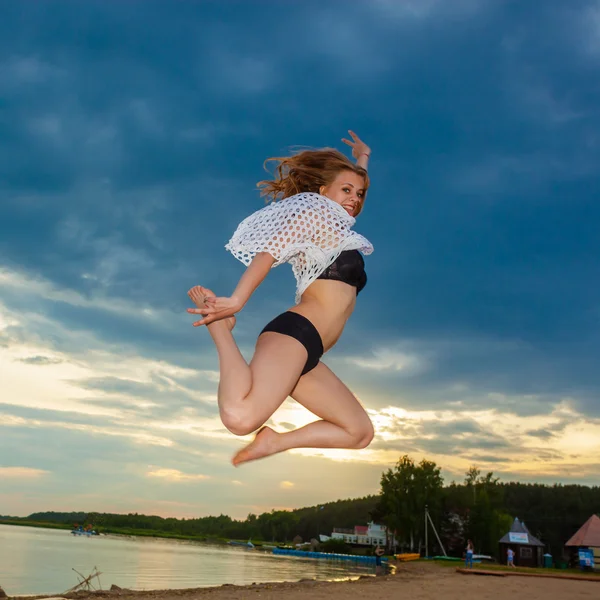 Dziewczynka skacze na plaży o zachodzie słońca — Zdjęcie stockowe