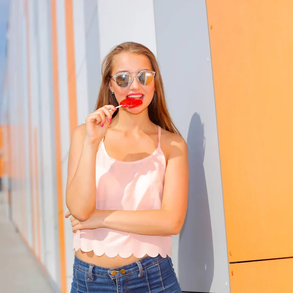 Vidám lány a napszemüveg a kezében szórakozni candy — Stock Fotó