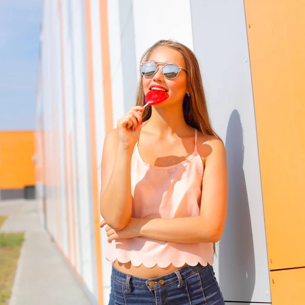 Glad flicka i solglasögon har kul med godis i händerna — Stockfoto