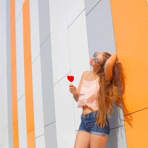 Vrolijk meisje in zonnebril hebben plezier met snoep in haar handen — Stockfoto