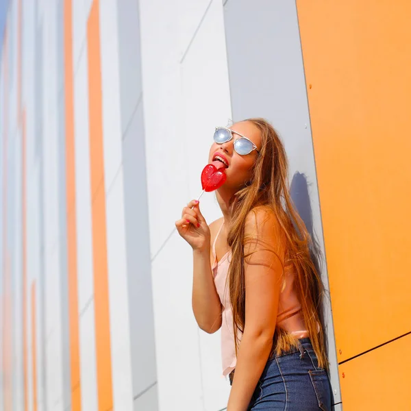 Glad flicka i solglasögon har kul med godis i händerna — Stockfoto