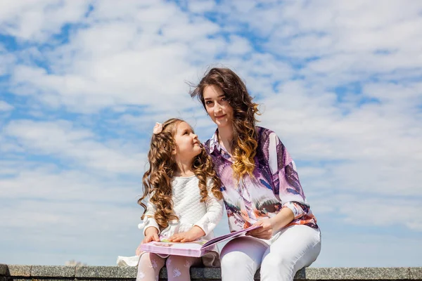 Mãe com filha ler um livro no parque — Fotografia de Stock