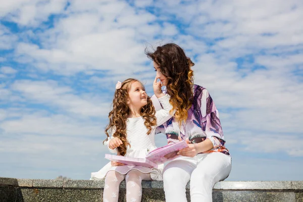 Mãe com filha ler um livro no parque — Fotografia de Stock