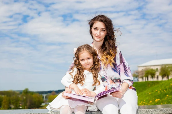 Madre con hija leyó un libro en el parque — Foto de Stock