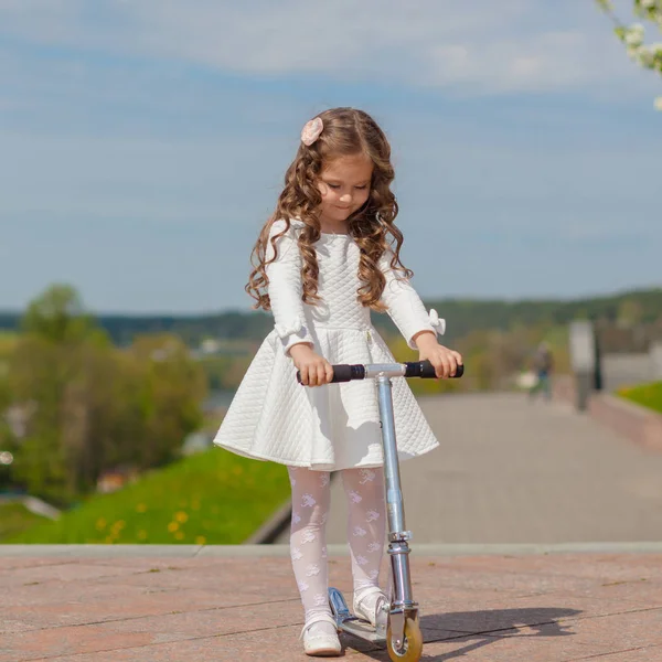 Dziewczyna gra na zewnątrz i jeździe na hulajnodze — Zdjęcie stockowe