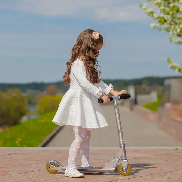 Dziewczyna gra na zewnątrz i jeździe na hulajnodze — Zdjęcie stockowe