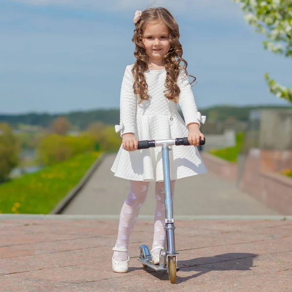 Girl playing outdoors and riding a scooter — Stock Photo, Image