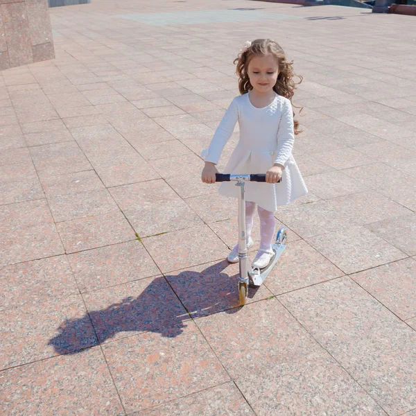 Девушка играет на открытом воздухе и ездит на скутере — стоковое фото