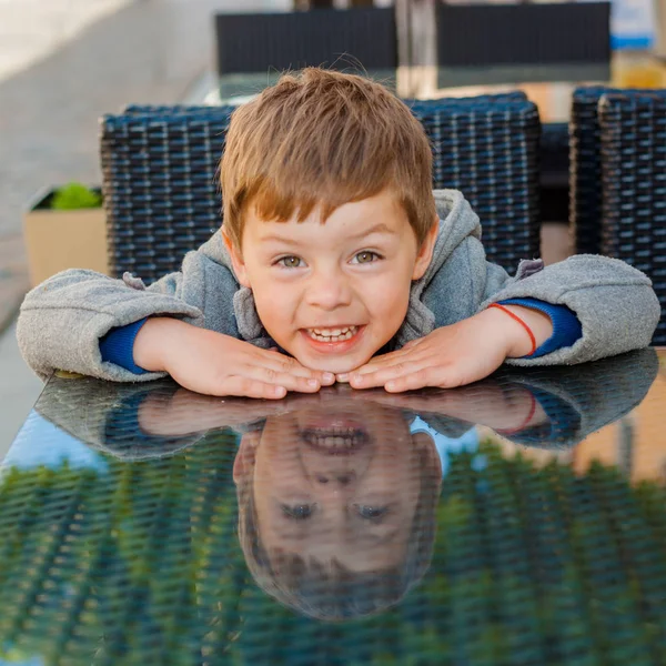 Emotional boy at a table in a cafe — Stock Photo, Image