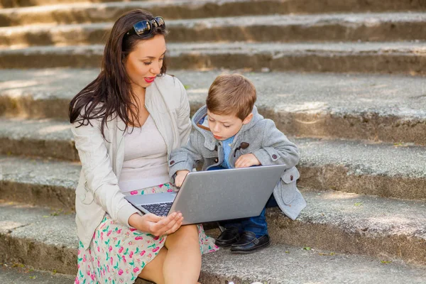 妈妈带儿子和笔记本电脑在公园里在楼梯上 — 图库照片