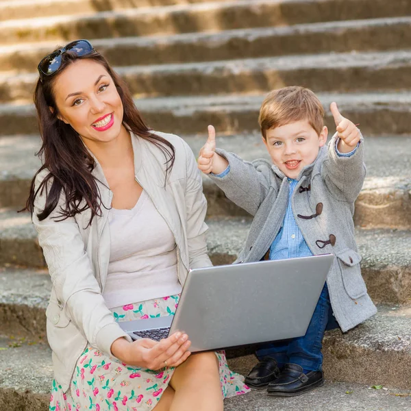 Mom with son and laptop on the stairs in the park