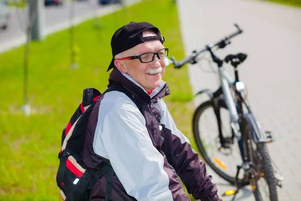 Bărbat în vârstă într-un costum sportiv care stă pe o bancă — Fotografie, imagine de stoc