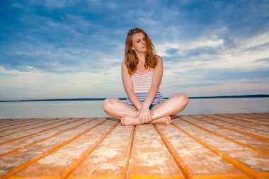 Sahilde günbatımı üzerinde meditasyon ahşap pier Girl on.