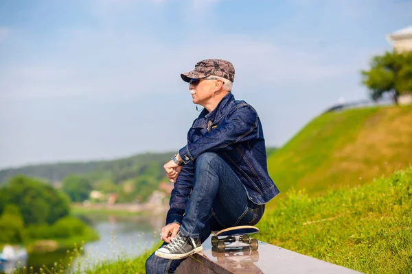 Dreamy hipster happy elderly man in sunglasses on blue sky background — Stock Photo, Image