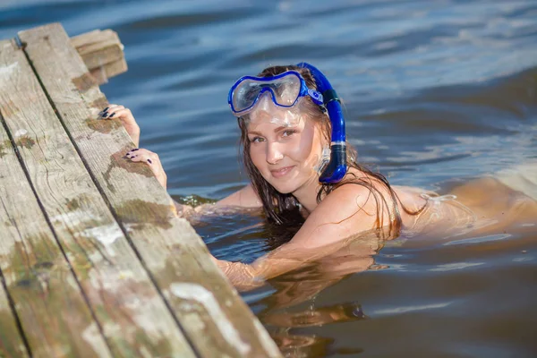 Glad dykning tjej i simning mask och snorkel nära den gamla träpiren. — Stockfoto