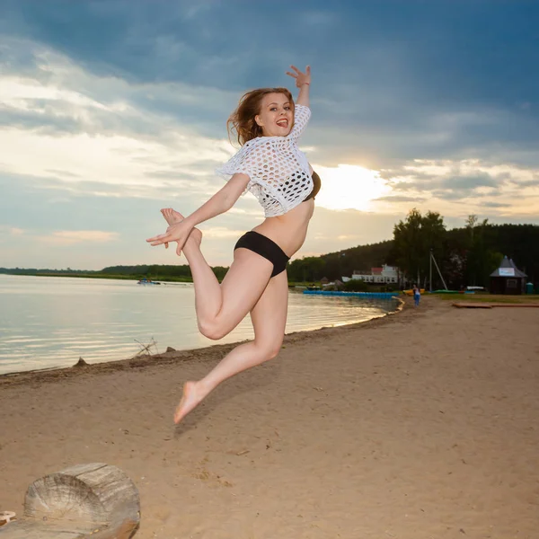 Дівчина стрибає на пляжі на фоні заходу сонця . — стокове фото