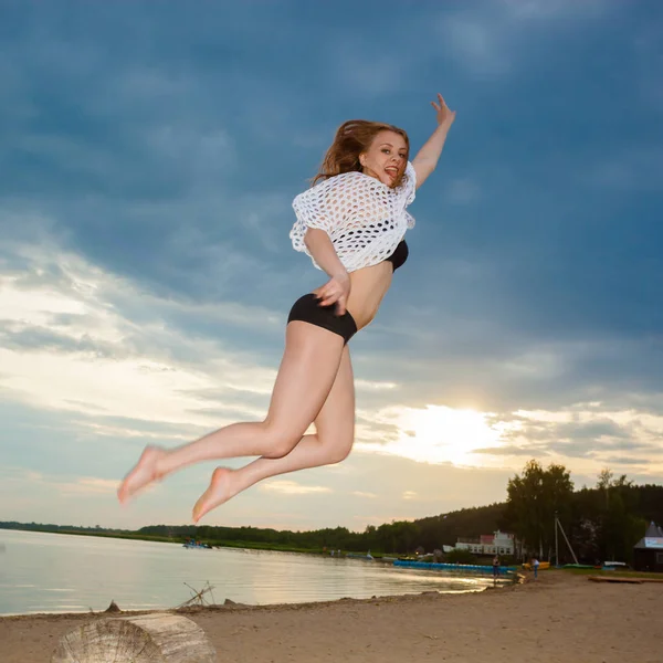 Dziewczyna, skoki na plaży przy zachodzie słońca tło. — Zdjęcie stockowe