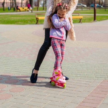 Anne ve kızı tekerlekli paten üzerinde binmek. Kız paten ve falls öğrenme. Anne kızı Silindirler binmek için öğretir