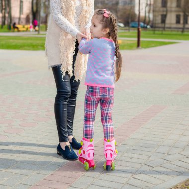 Anne ve kızı tekerlekli paten üzerinde binmek. Kız paten ve falls öğrenme. Anne kızı Silindirler binmek için öğretir