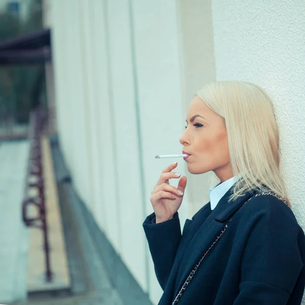 Крупный план сексуальной женщины в солнечных очках и белой рубашке, курящей сигару — стоковое фото