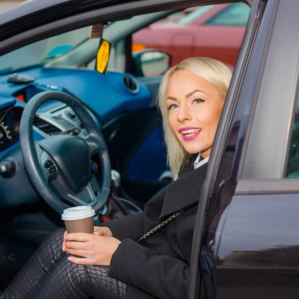 Bir fincan kahve ile arabada direksiyonda iş kadını. — Stok fotoğraf
