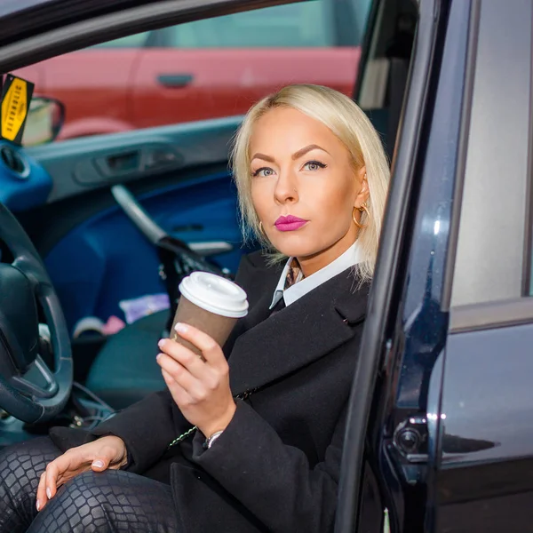 Üzletasszony: a kerék az autóban, egy csésze kávé. — Stock Fotó