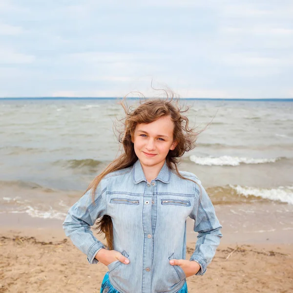 Beautiful teenager girl on a windy autumn beach. — Stock Photo, Image