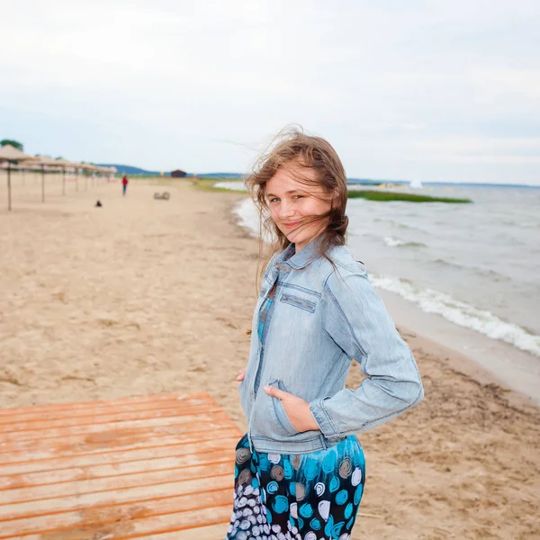 Beautiful teenager girl on a windy autumn beach. — Stock Photo, Image