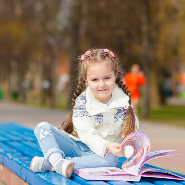 Adorable mignon livre de lecture de petite fille. Adorable petit livre de lecture fille dans le jardin - extérieur — Photo