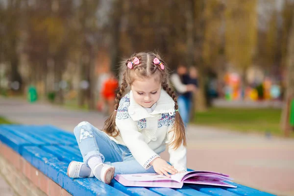 Adorable mignon livre de lecture de petite fille. Adorable petit livre de lecture fille dans le jardin - extérieur — Photo