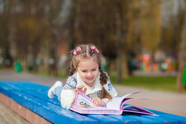 Adorable cute little girl reading book. Adorable little girl reading book in the garden - outdoor — Stock Photo, Image